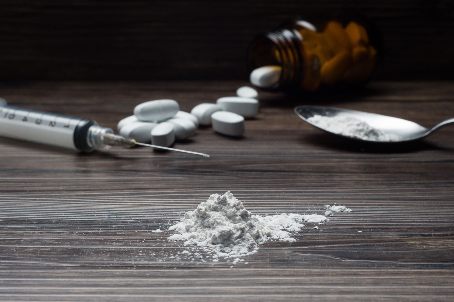 Drugs set - powder and pills and syringe on wooden background